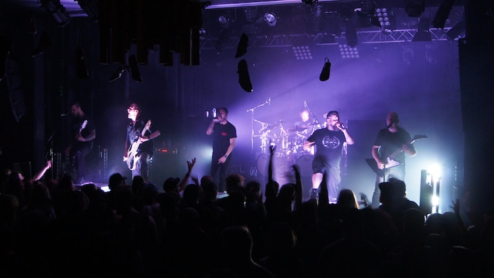 6 hommes font de la musique sur une scène.