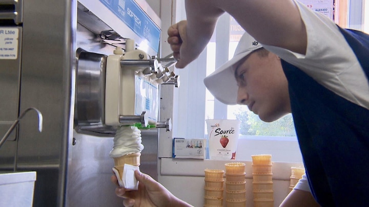 Un adolescent est en train de faire un cornet de crème glacée.