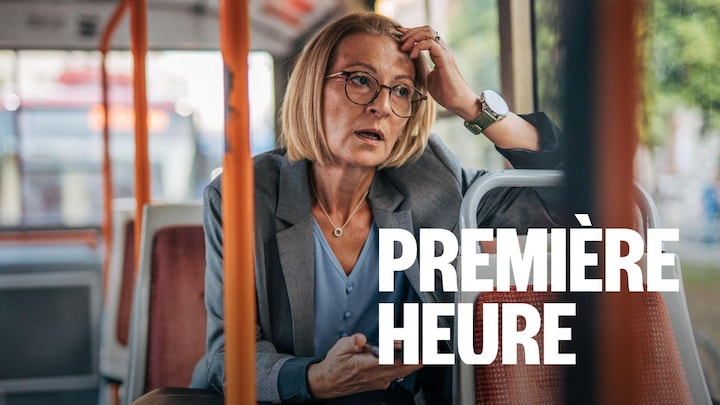 Une femme se tient la tête d'une main et tient son téléphone cellulaire de l'autre.