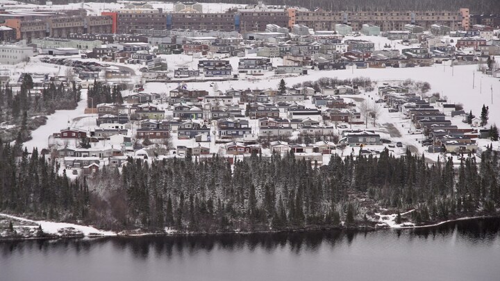 Gros plan de la ville de Fermont, où on voit des dizaines de maisons, le mur de Fermont et un lac.