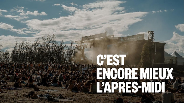 Des gens sont assis dans le sable devant une scène.