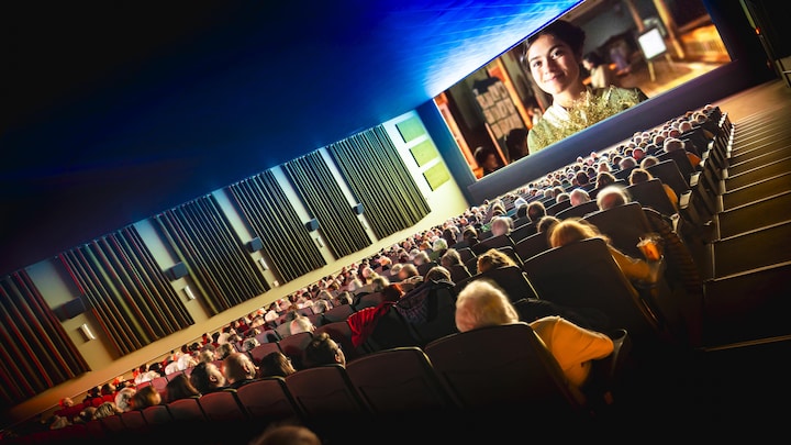 Des gens assis dans une salle de cinéma qui regarde un film.
