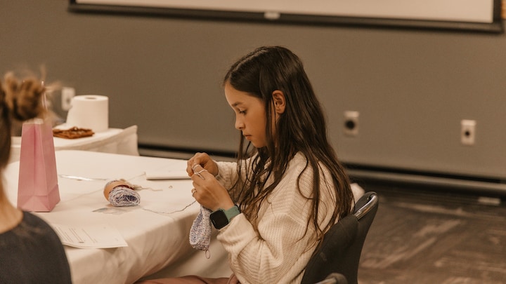 Une fillette tricotte, concentrée.