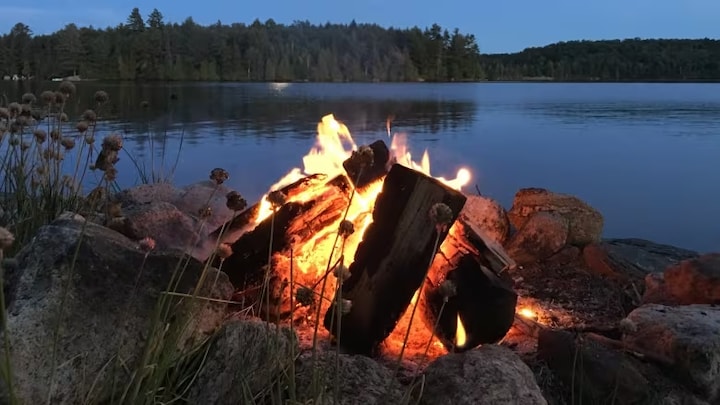 Un feu de campy  brille juste après la tombée de la nuit sur le lac Joseph dans la région de Muskoka en Ontario.
