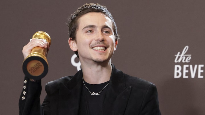 Il tient son trophée dans la main droite.