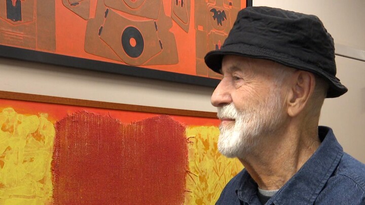 Un homme ainé de profil, rêveur, la tête dans ses œuvres d'art. 
