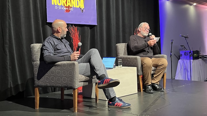 Martin Guérin et Gildor Roy sont assis dans des fauteuils, micros à la main, au Centre des congrès de Rouyn-Noranda.