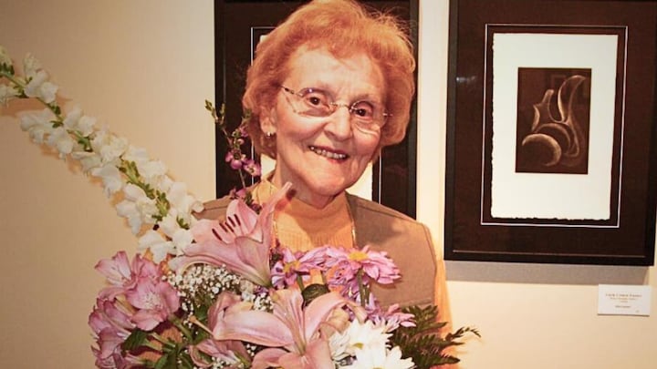 Gisèle Cotnoir-Lussier sourit et tient un bouquet de fleurs.