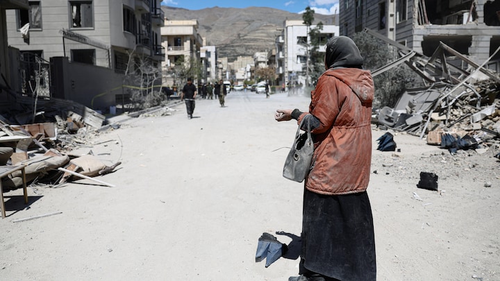 Une femme se tient debout sur une route dans un quartier résidentiel endommagé par une frappe dans le cadre du conflit entre les États-Unis, Israël et l'Iran, à Téhéran, en Iran, le 30 mars 2026. 