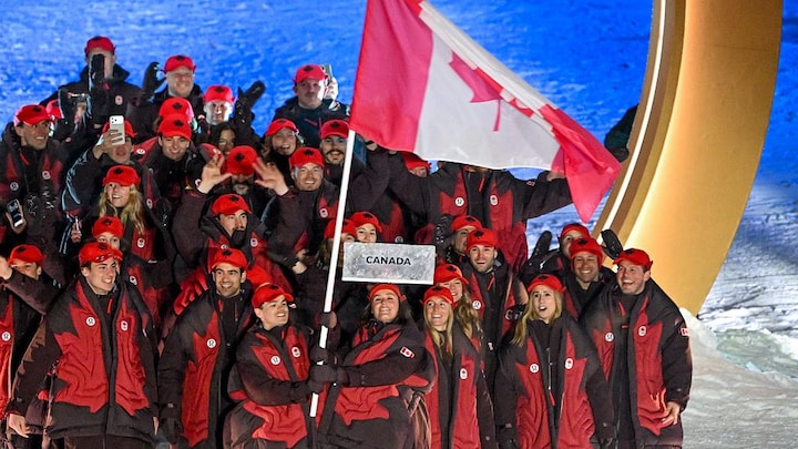 Les porte-drapeaux canadiens Marielle Thompson et Mikael Kingsbury défilent avec leur équipe lors de la cérémonie d'ouverture des Jeux olympiques.