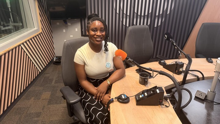 Jovial Orlachi Osundu pose pour la photo dans un studio de radio devant un microphone.