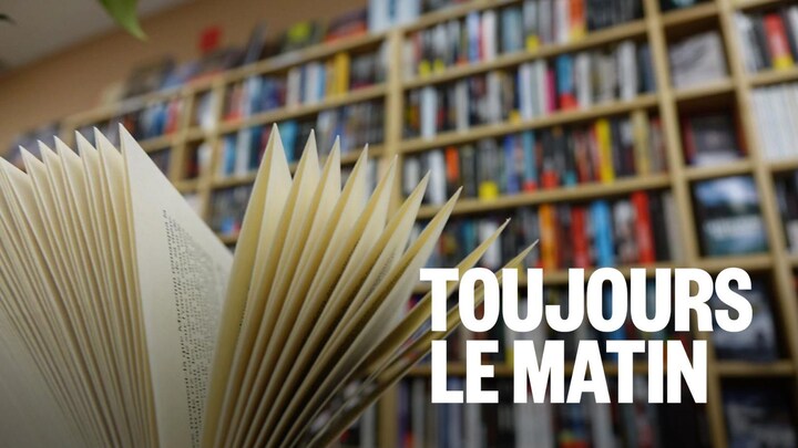 En avant-plan, un livre ouvert devant une bibliothèque bien remplie