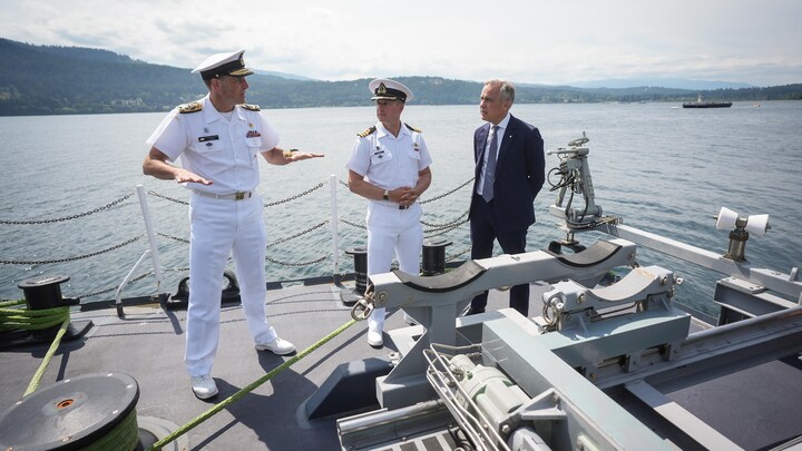 Deus commandants de la marine et Mark Carney sur un navire.