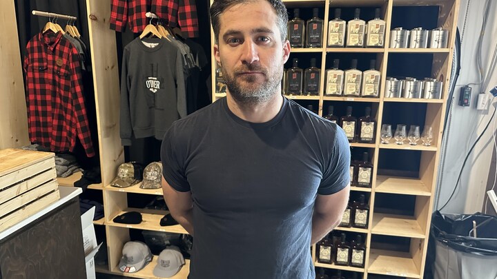 Michael Briand, propriétaire de la distillerie O'Dwyer, devan une étagère d'alcool.