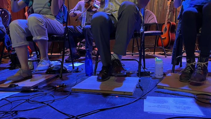 Des violonistes tapent du pied sur la scène.