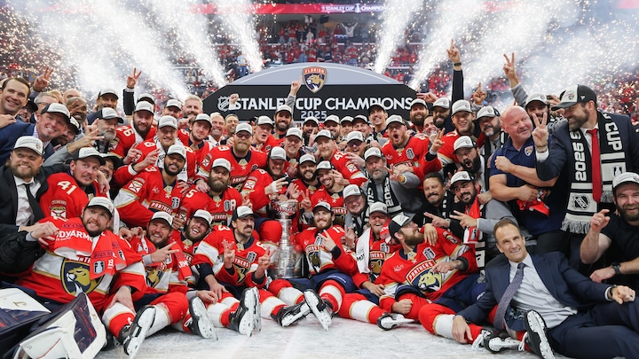 Tous les joueurs et membres du personnel des Panthers, souriants, posent sur la glace autour de la coupe Stanley pour une photo d'équipe devant une foule en liesse.