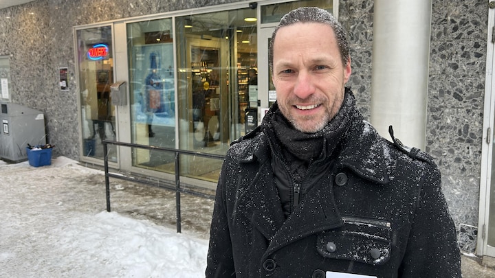 Un homme devant une succursale de la SAQ.