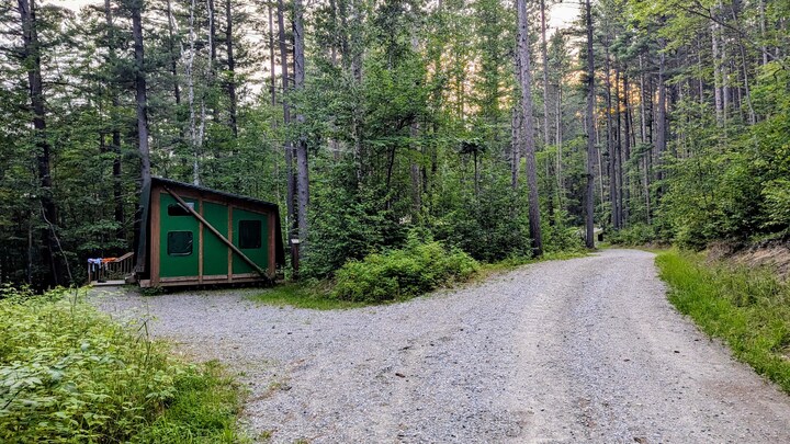 Une route en gravelle mène à une cabine en bois et en toile.