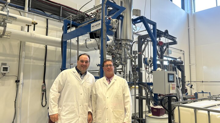 Les copropriétaires de Propane 418, Charles Couturier (à gauche) et Marc-Olivier Corbeil, devant un distillateur moléculaire dans une usine, en sarrau.