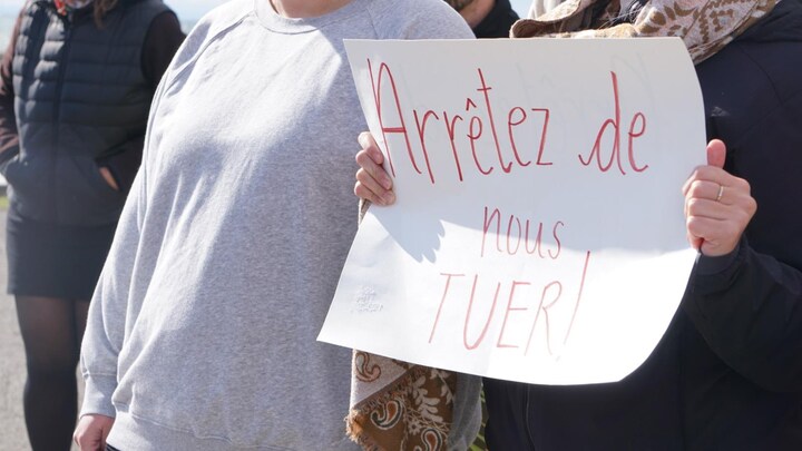 Un femme tient une pancarte sur laquelle on peut lire « arrêtez de nous tuer ».