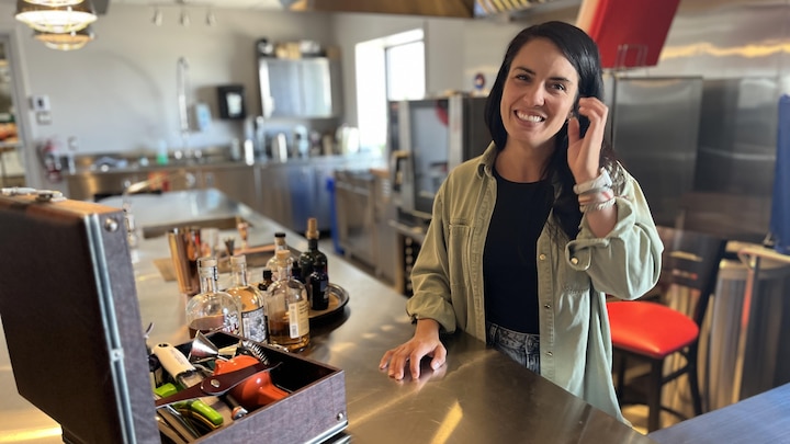 Une femme sourit à la caméra, dans une cuisine.