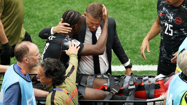 Assis sur une civière, Koné fait une accolade à son entraîneur.