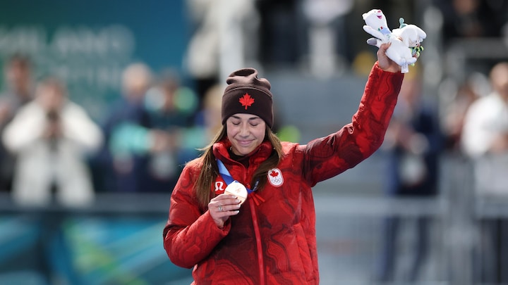 Une athlète regarde sa médaille sur le podium.