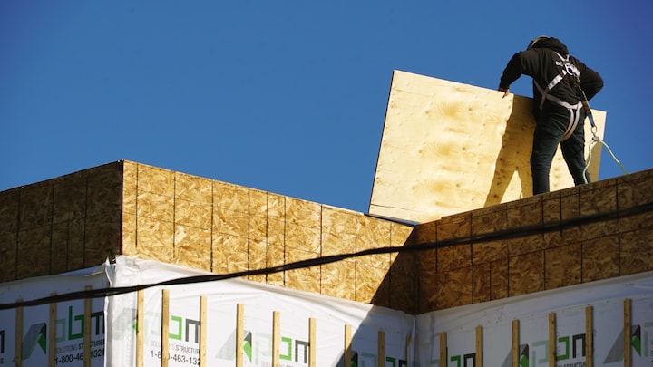 Un travailleur sur le toit d'une maison en construction.