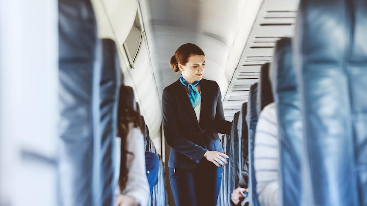 Une agente de bord dans l'allée d'un avion. 