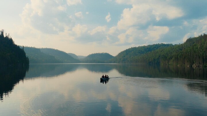 Lac calme entouré de forêt à la Pourvoirie des Bouleaux Blancs, avec une chaloupe à l'eau.