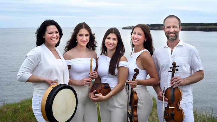Une famille (trois jeunes femmes entournées de leurs parents) dont les membres sont vêtus en blanc. On voit une grande étendue d'eau derrière eux.