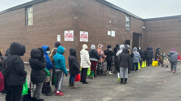 Une vingtaine de personnes debout font la queue.