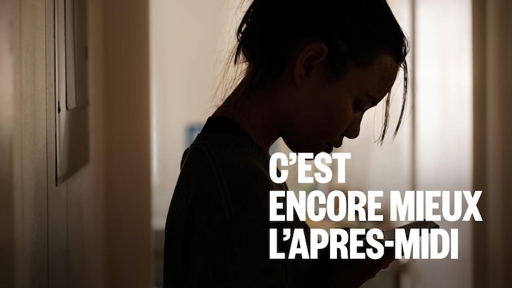 Une jeune fille dans l'ombre regarde son téléphone intelligent.