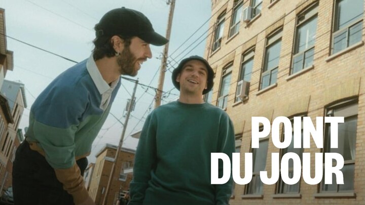 Deux hommes souriants dans une rue ensoleillée.