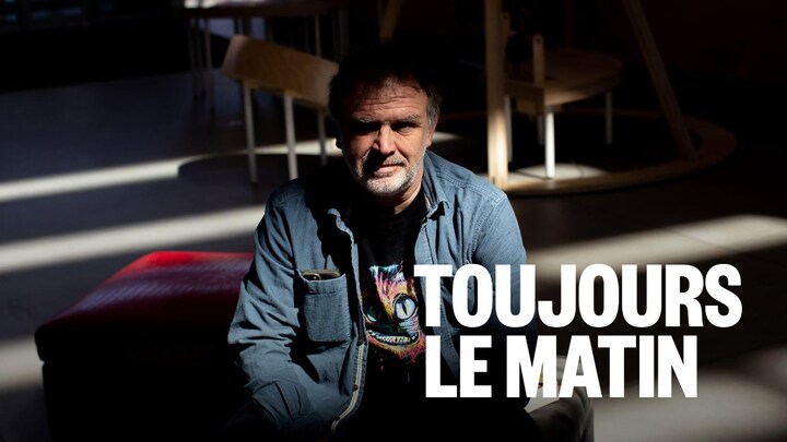 Il est assis dans le noir.