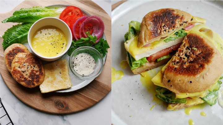 Plusieurs ingrédients (pain, tomate, salade, oignons, sauces, persil) présentés sur une assiette pour composer un sandwich.