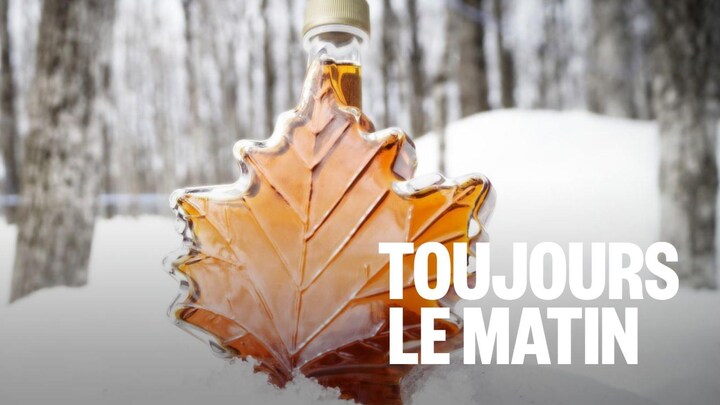Une bouteille de sirop dans un boisé posée sur la neige.