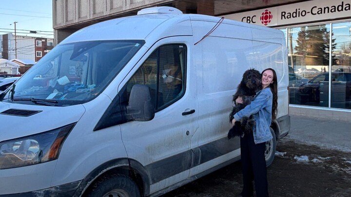 Portrait de Marie Darsy tenant son chien dans ses bras devant son véhicule récréatif.