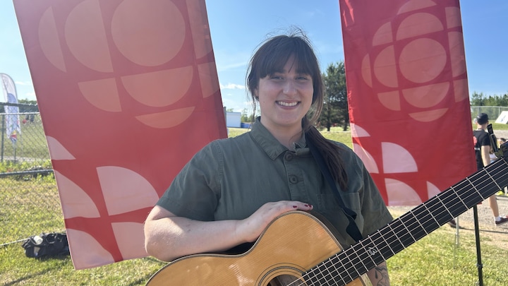 Caroline Savoie debout avec sa guitare.
