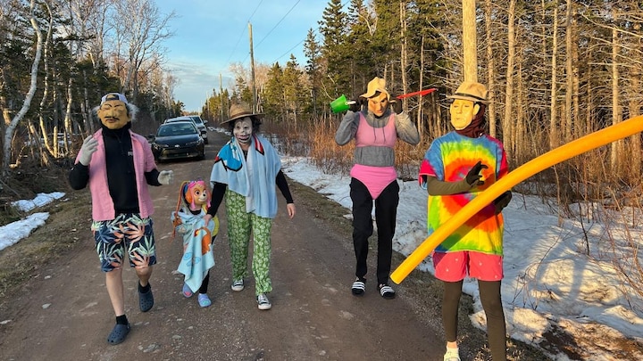 Quatre adultes et un enfants costumés marchent dans un sentier.