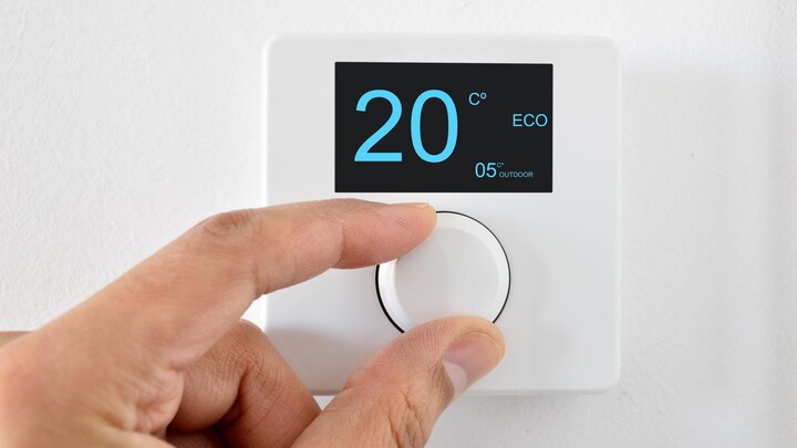 Quelqu'un règle un thermostat mural.
