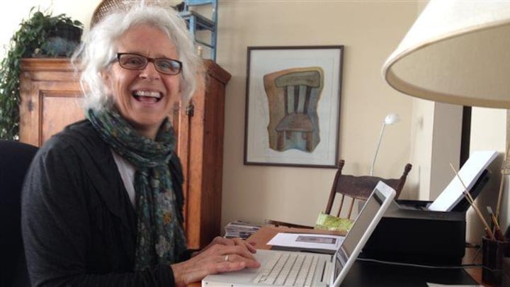 Une femme souriante devant son ordinateur portable.