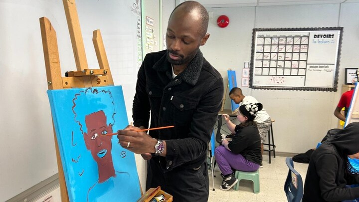 Mike Kasongo peint dans une salle de classe.