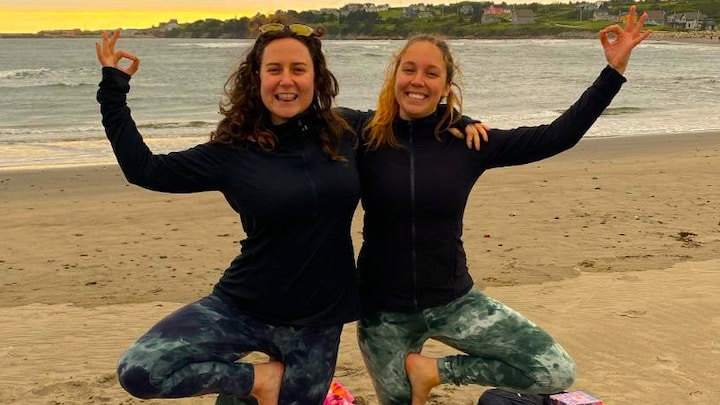 Deux personnes font une pose de yoga sur une plage.