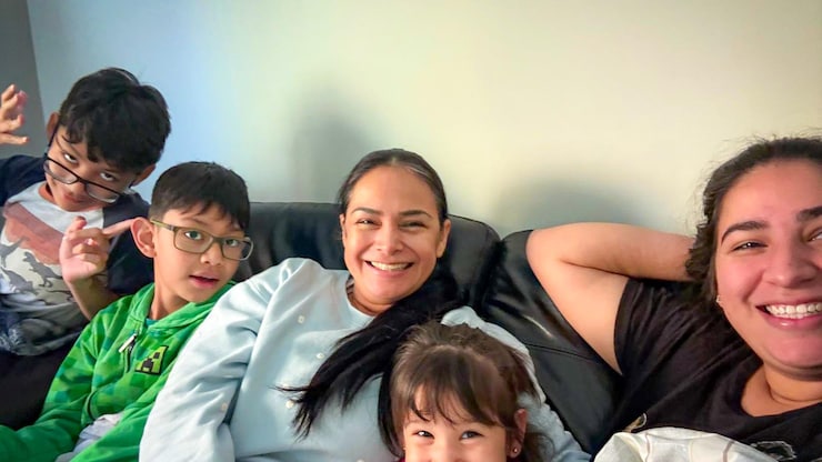 Une famille assise dans un canapé en train de sourire.