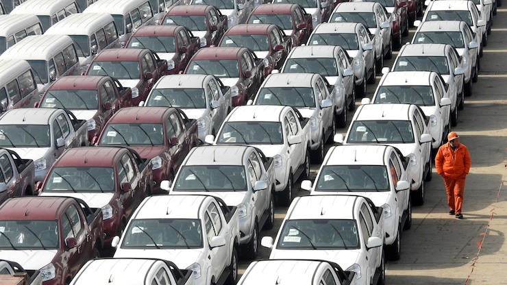 Un trabajador camina junto a coches y furgonetas destinados a la exportación en el puerto de Lianyungang, en la provincia de Jiangsu, en China.