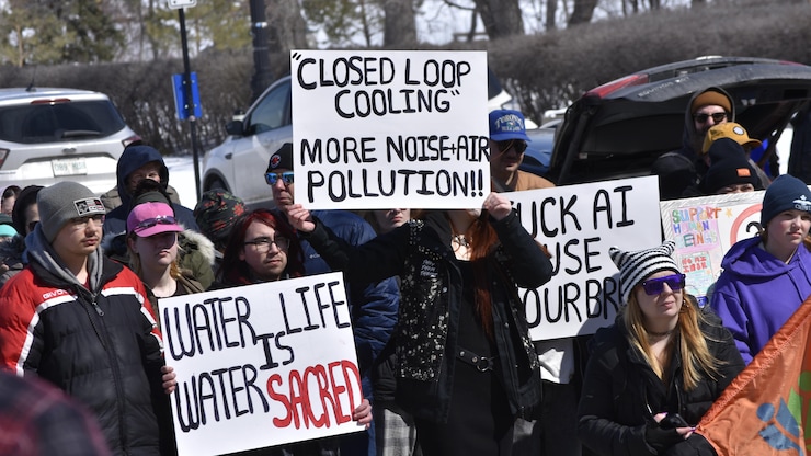 Des manifestants par temps froid, brandissant des pancartes avec des slogans exprimant leur opposition à un centre de données à cause de la pollution de l'eau et du bruit.