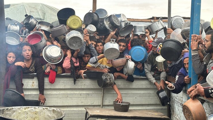 Dozens of children hold pots out at a food distribution kitchen in the south of Khan Younis City in southern Gaza Friday. 