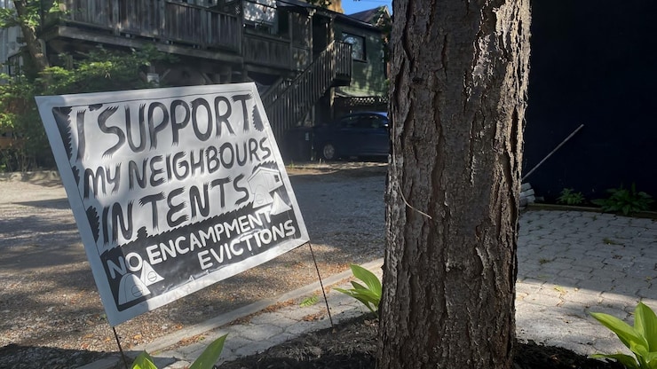 ES: Cartel junto a un árbol: "APOYO A MIS VECINOS EN CARPAS NO A LOS DESALOJOS DE CAMPAMENTOS".
FR: Pancarte près d'un arbre : "JE SOUTIENS MES VOISINS EN TENTE NON AUX EXPULSIONS DE CAMPEMENTS".
EN: Yard sign near a tree: "I SUPPORT MY NEIGHBOURS IN TENTS NO ENCAMPMENT EVICTIONS".
