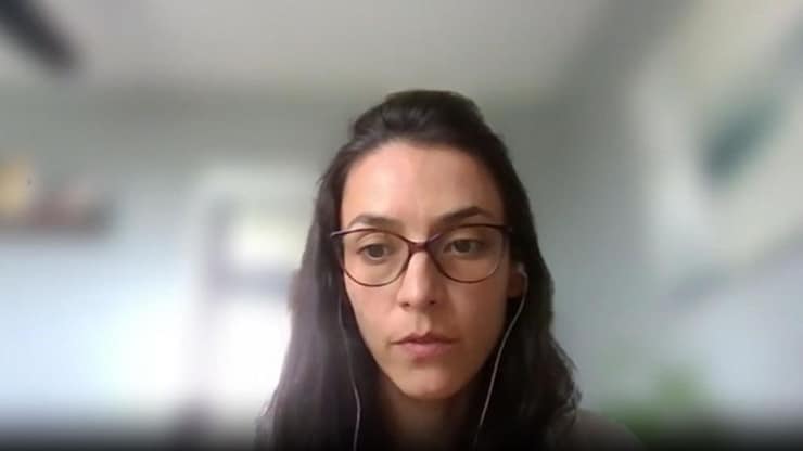 ES: Mujer con gafas y auriculares en una videollamada, mirando atentamente con fondo desenfocado.
FR: Femme à lunettes et écouteurs lors d'un appel vidéo, regardant attentivement avec un fond flou.
EN: Woman with glasses and earphones on a video call, looking intently against a blurred background.